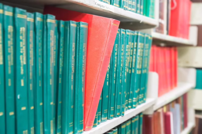 A single red book standing out among rows of teal academic journals in a school library, symbolizing the "Academic Trap" in K-12 program evaluation.